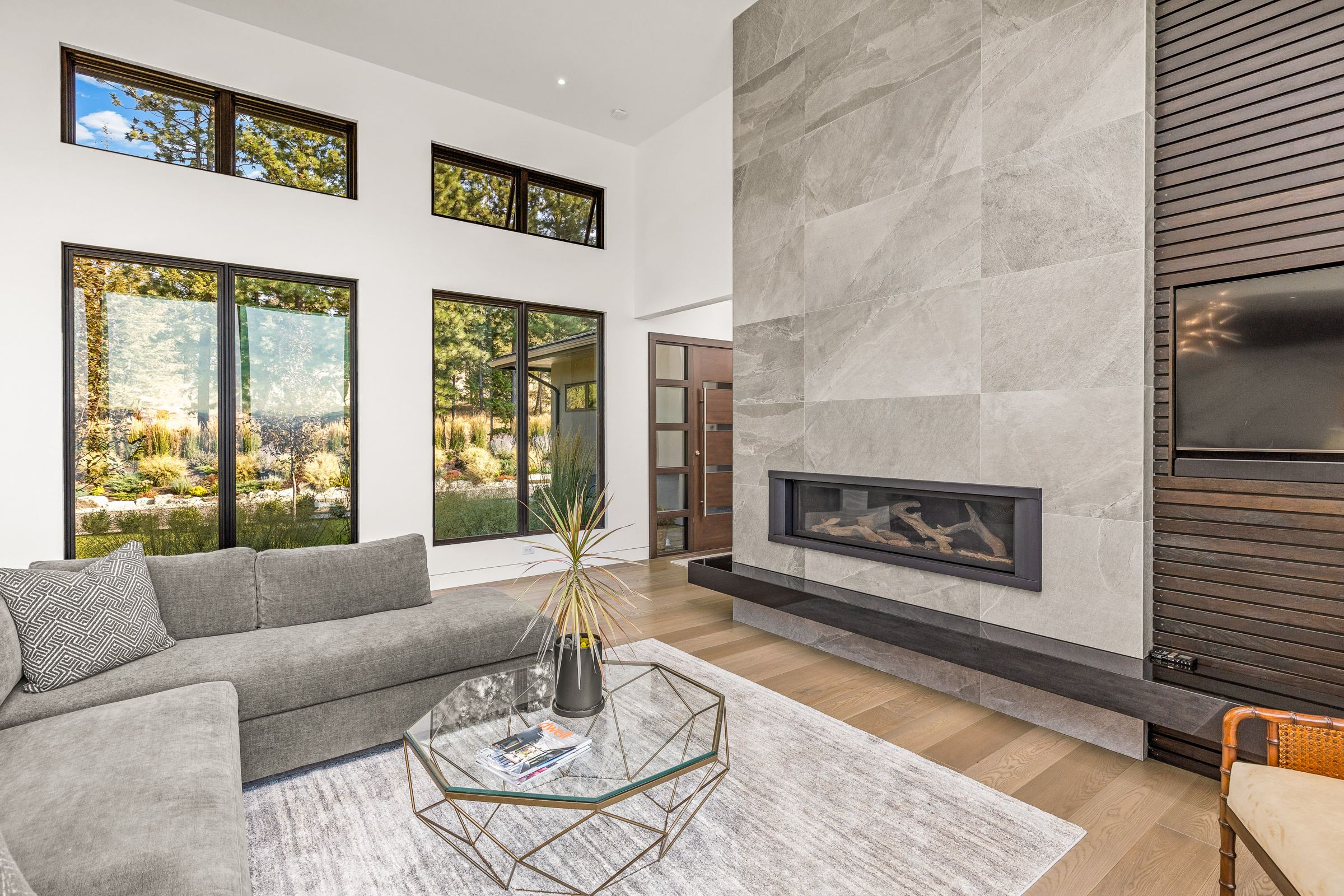 Living room with a linear gas fireplace and floor to ceiling windows onto a valley view